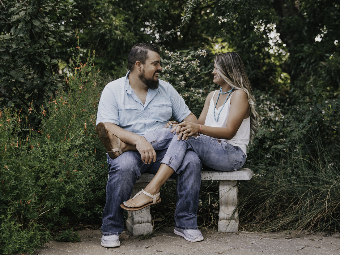 Dustin and Jaci Statton sit on a bench in an engagement photo from 2021.