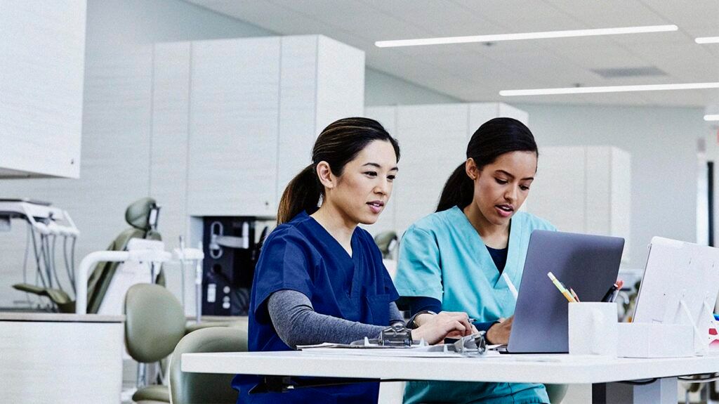 Two healthcare professionals looking at a laptop to discuss when an urgent colonoscopy might be necessary -2.