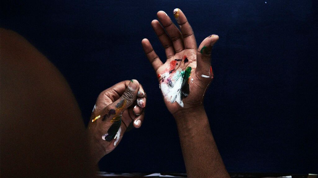 Closeup of a person's hands with paint on the palm and thumb.