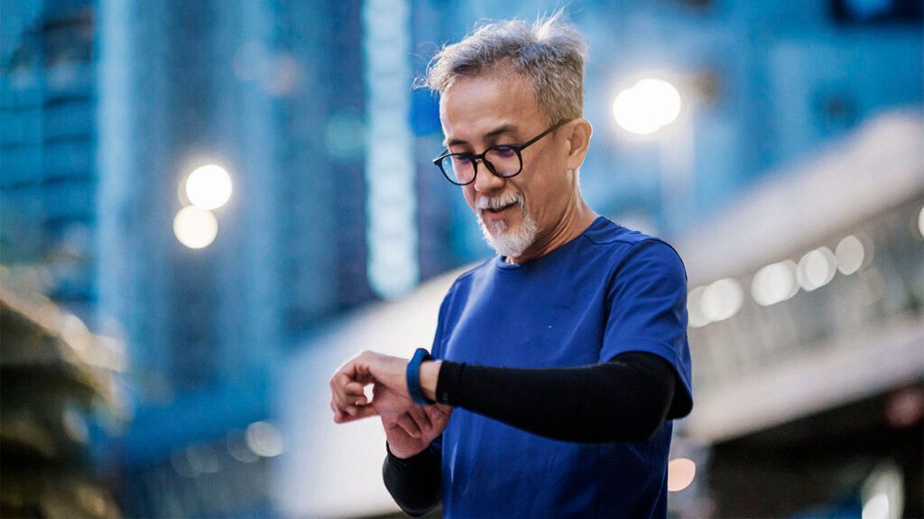 Older male checking his heart rate on a fitness watch on a city street