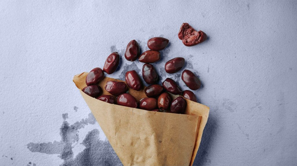 Black olives in a paper bag on a flat surface