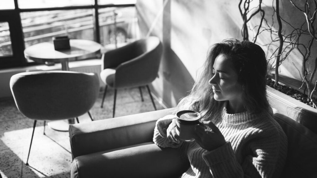 black and white photo of woman drinking a cup of coffee