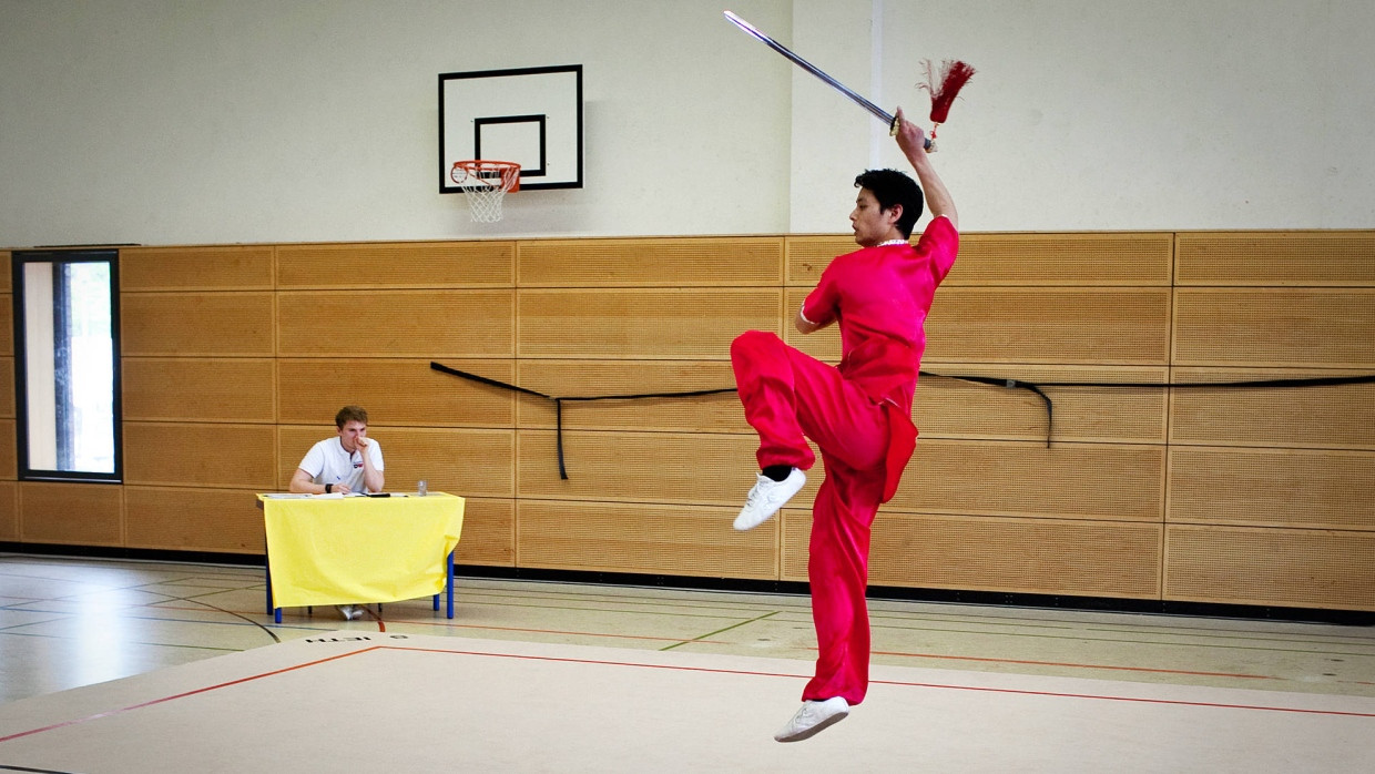 Scheingefecht: Christoph Huynh springt und schwingt die Kurzwaffe - der Wushu-Kampfrichter schaut genau hin