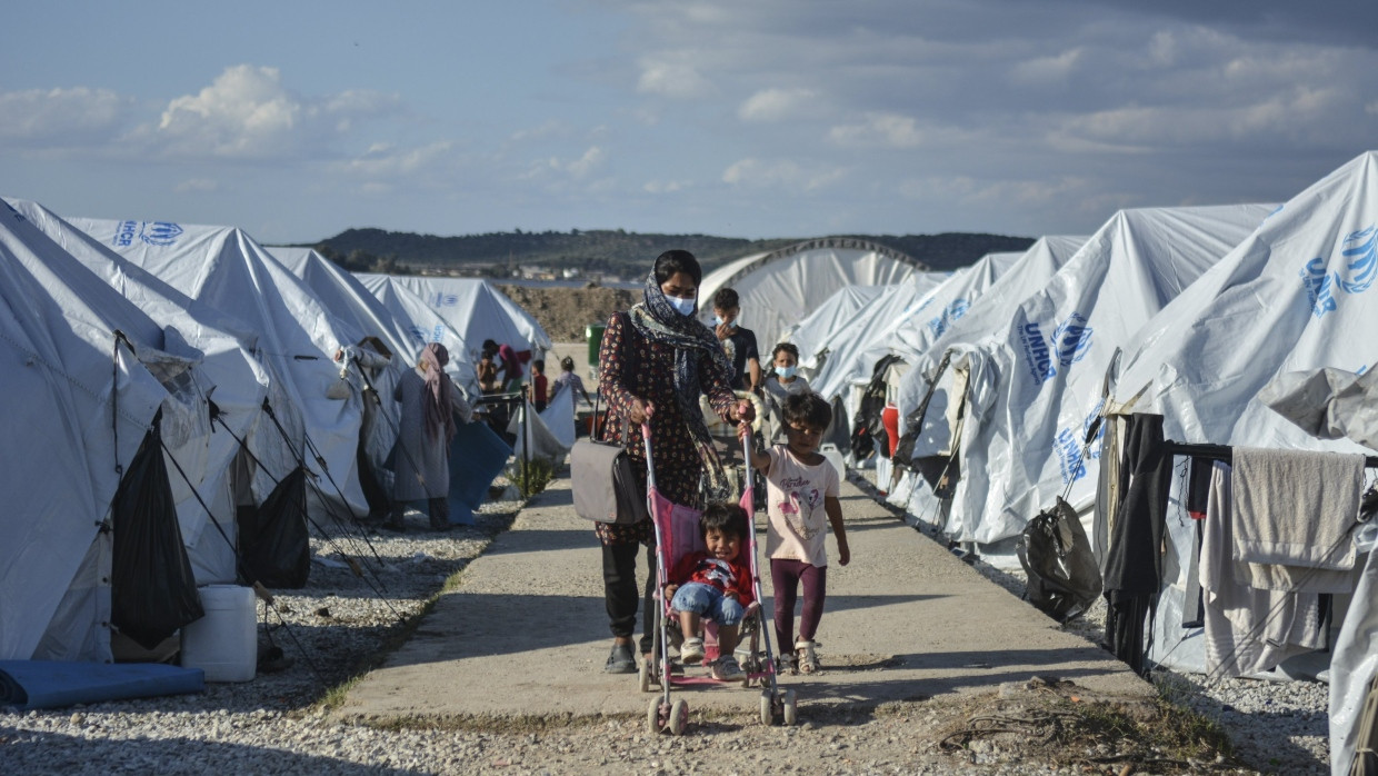 Migranten gehen nach einem starken Regenfall durch ein Flüchtlingslager auf Lesbos.