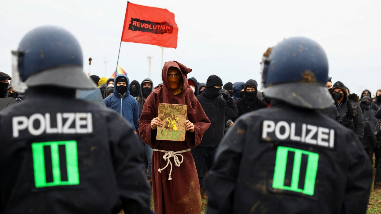 Vermummte und Polizisten bei den Braunkohleprotesten, dabei ein Demonstrant, der als Mönch verkleidet war.