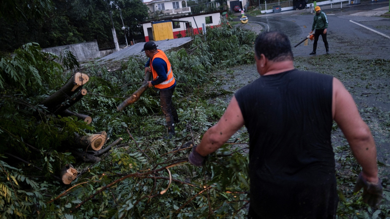 Menschen befreien eine Straße von einem umgestürzten Baum, nachdem der Hurrikan „Fiona“ das Gebiet in Yauco, Puerto Rico, am 18. September 2022 heimgesucht hat.