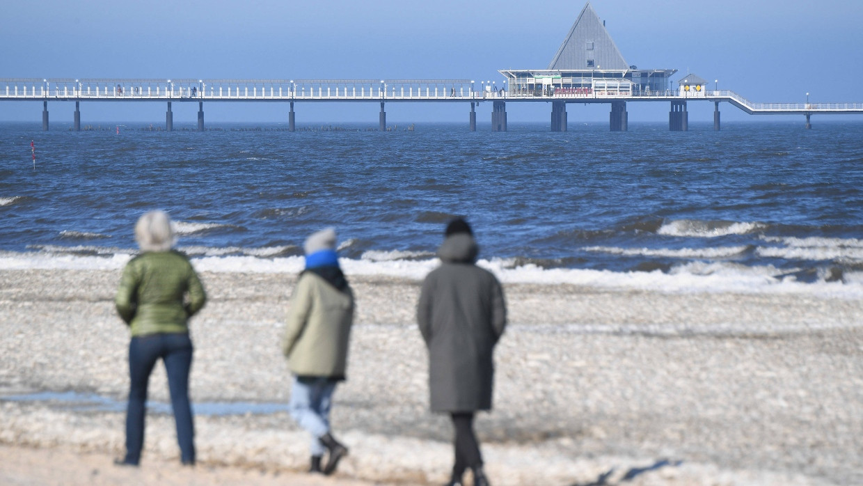 Spaziergänger sind am Strand von Ahlbeck auf der Insel Usedom unterwegs.