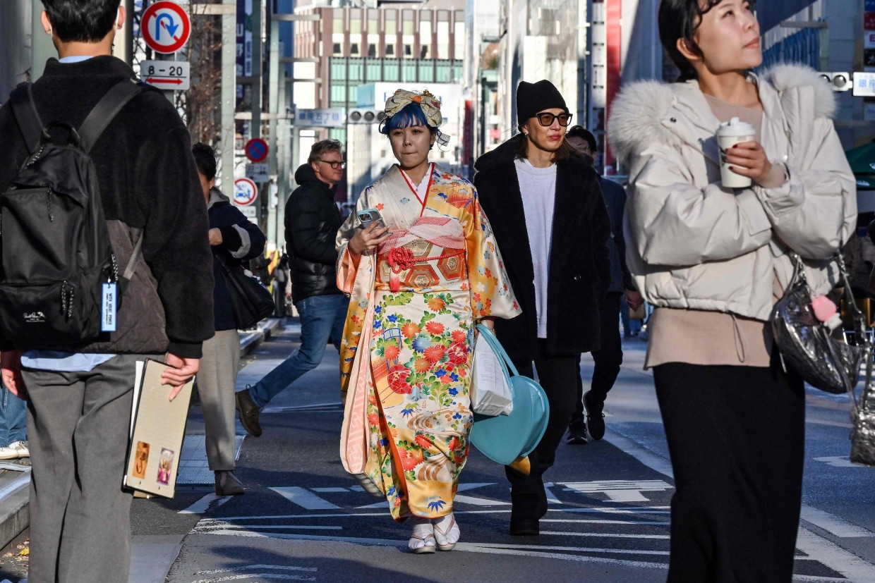 Eine junge Frau im bunt gemusterten Kimono geht entlang einer Straße im Tokioter Stadtteil Ginza.