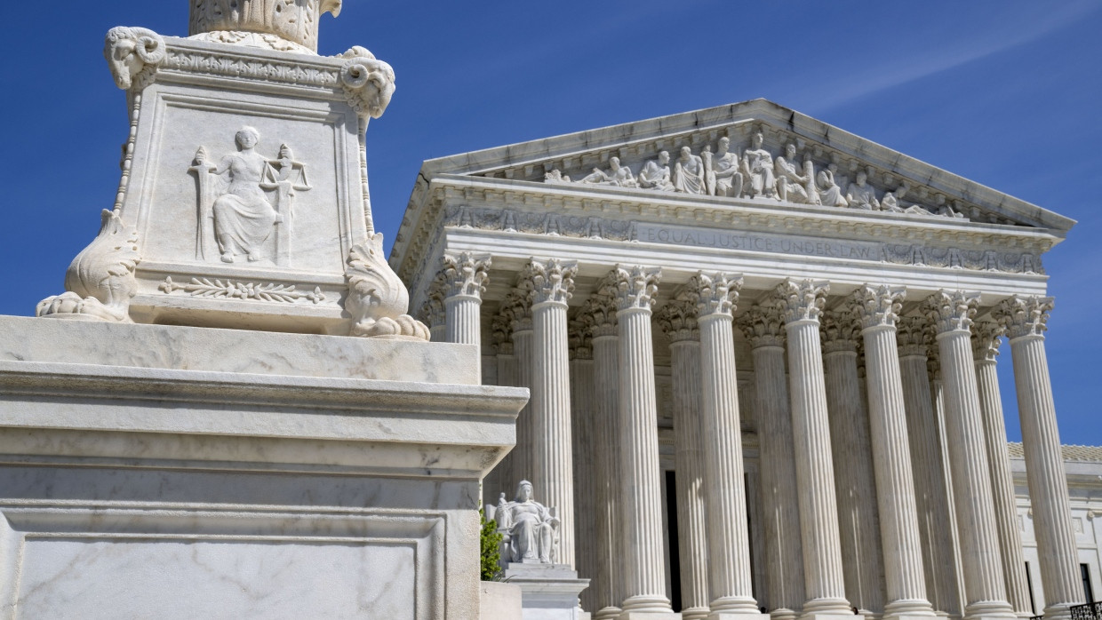 The U.S. Supreme Court is seen, with a carving of Justice in the foreground