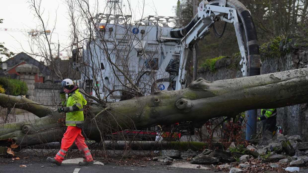 Arbeiter begutachten einen umgestürzten Baum, der durch die Mauer des Phoenix Parks und auf die Blackhorse Avenue in Dublin gestürzt ist.