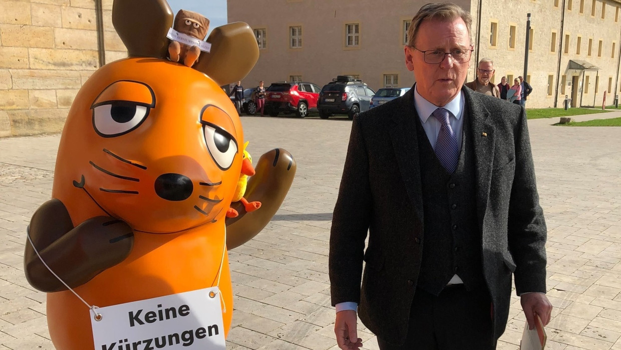 Bodo Ramelow steht neben der entführten Mausfigur, die ein Plakat mit der Aufschrift trägt „Keine Kürzungen bei ARD und ZDF!“. Die Aktivisten von Campact e.V. wollen mit der Maus ein Zeichen gegen Kürzungen im Informations- und Bildungsangebot des öffentlich-rechtlichen Rundfunks setzen.