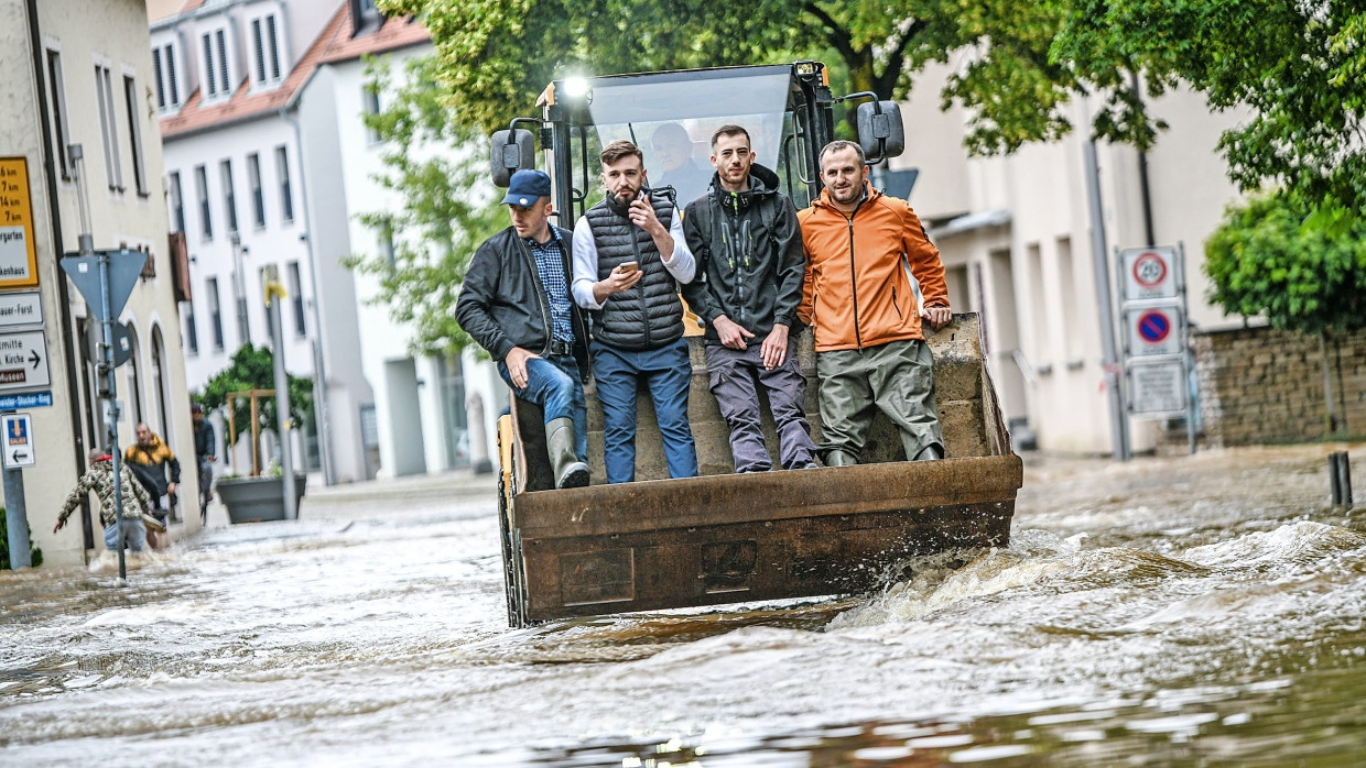 Durch die Fluten: In Schrobenhausen retten Helfer am Sonntag Menschen mit einem Radlader aus ihren Häusern und bringen sie in Sicherheit.