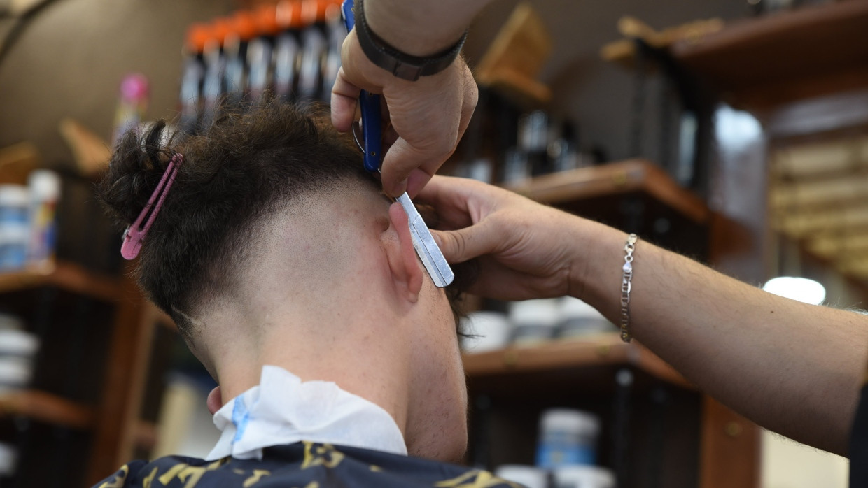 Ein Friseur rasiert in einem Barbershop die Haare eines männlichen Kunden (Symbolbild).