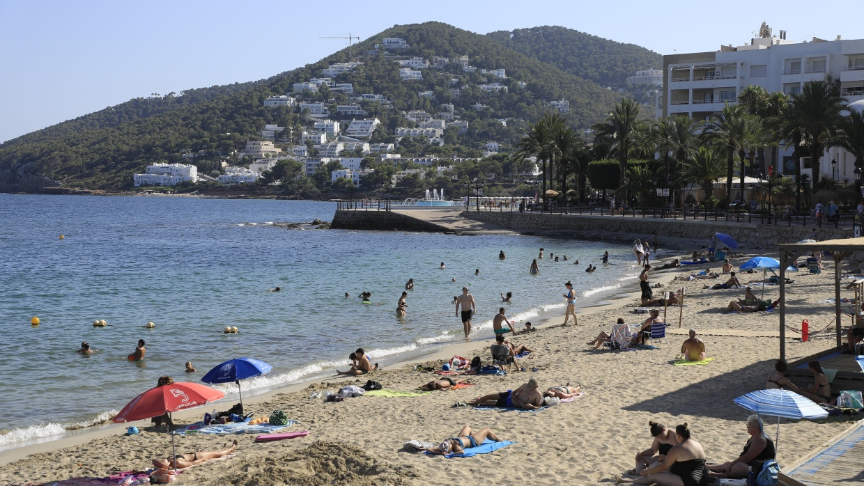 Menschen sonnen sich am Strand von Santa Eulalia auf Ibiza.