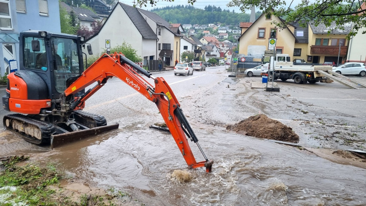 Schriesheim in Baden-Württemberg: Mit einem kleinen Bagger wird im Stadtteil Altenbach versucht, den Bestbach frei zu schaufeln, um das Wasser von der überfluteten Sraße abfließen zu lassen.