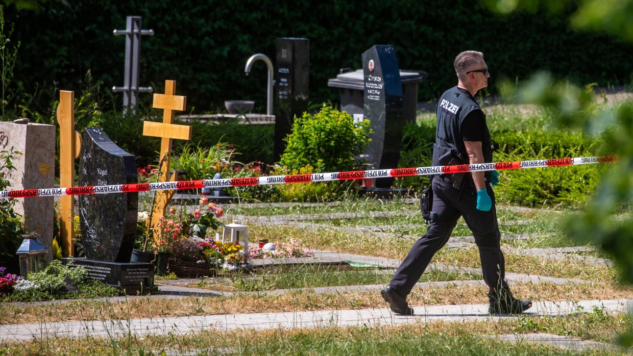 Ein Polizist läuft über den abgesperrten Teil des Friedhofs in Altbach.