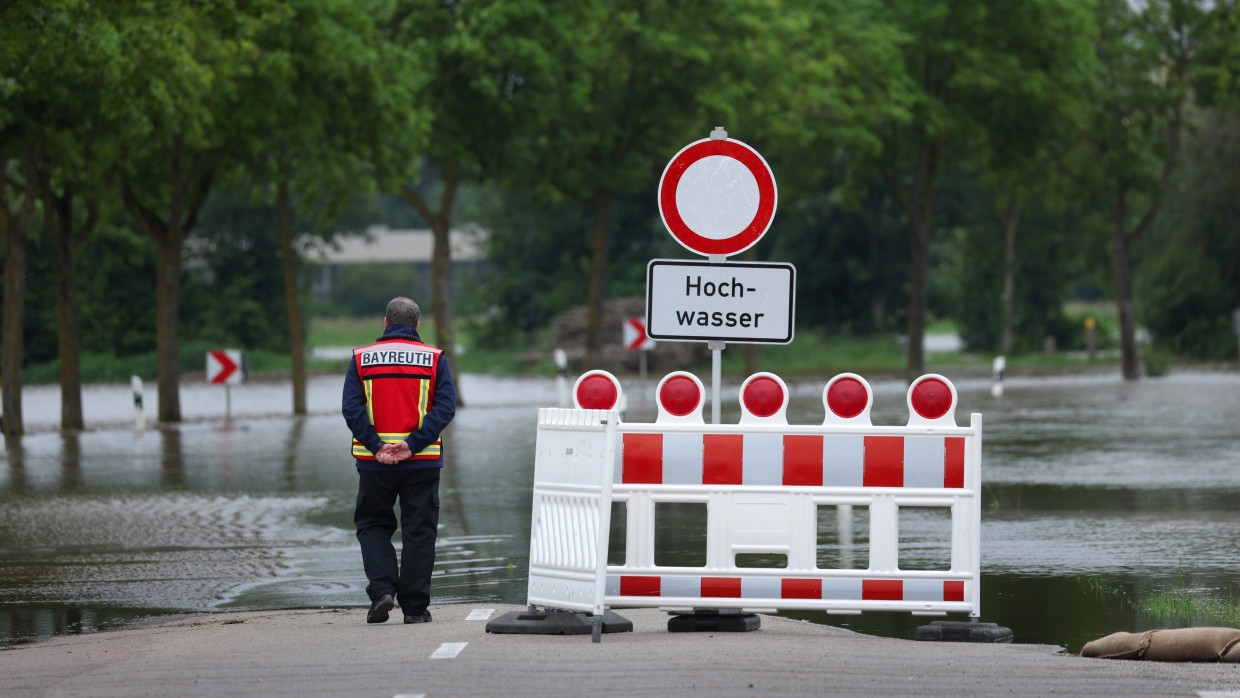 Im bayerischen Asbach-Bäumenheim begutachtet ein Feuerwehrmann eine vom Hochwasser überflutete Straße.