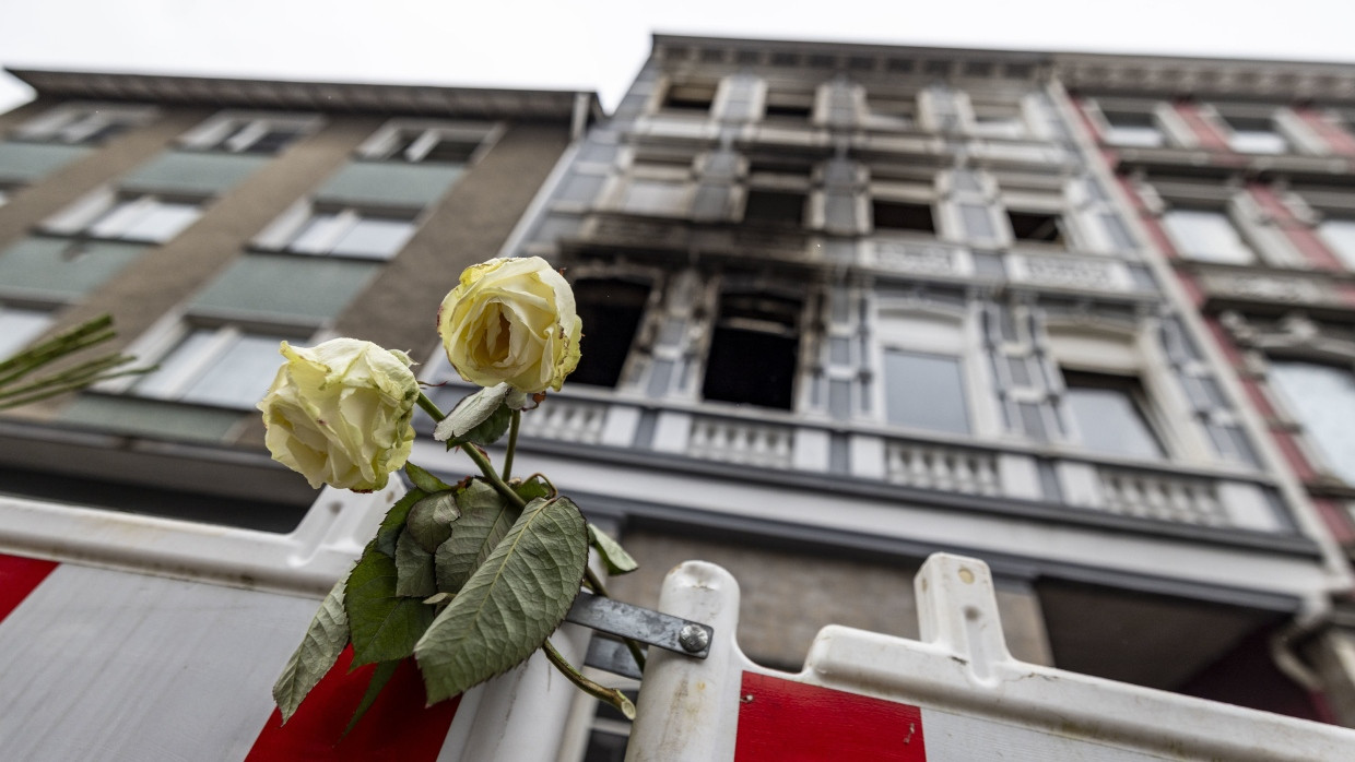 Eine weiße Rose klemmt an einer Absperrbake vor dem Brandort in Solingen.