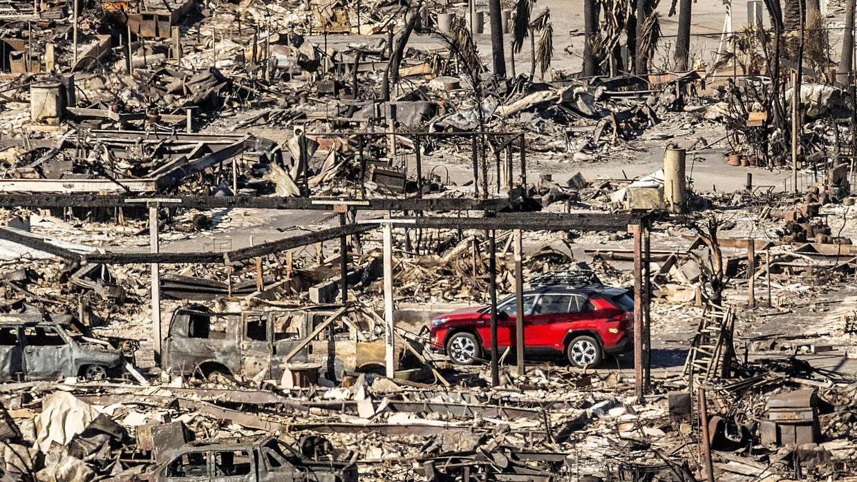 Nach dem Feuer: Ein Auto fährt durch einen zerstörten Straßenzug in Pacific Palisades.