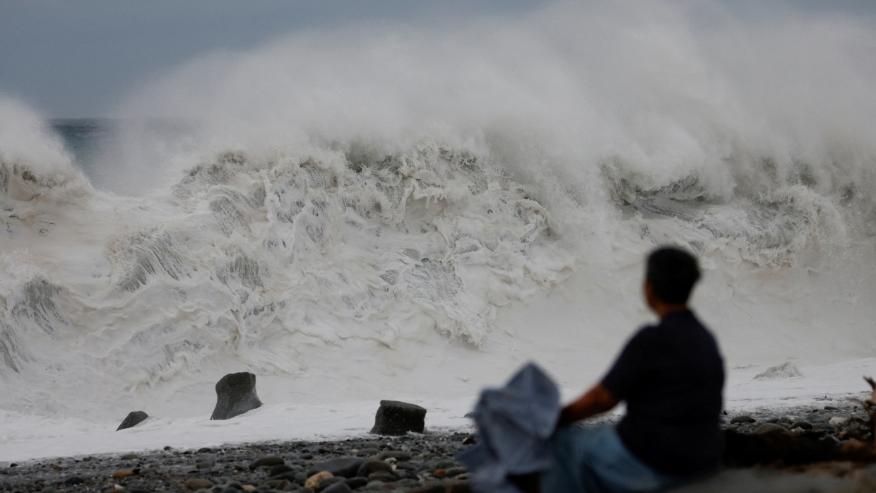 Am Mittwoch, bevor der Taifun auf Taiwan trifft, sitzt eine Frau am Strand an Taiwans Ostküste.