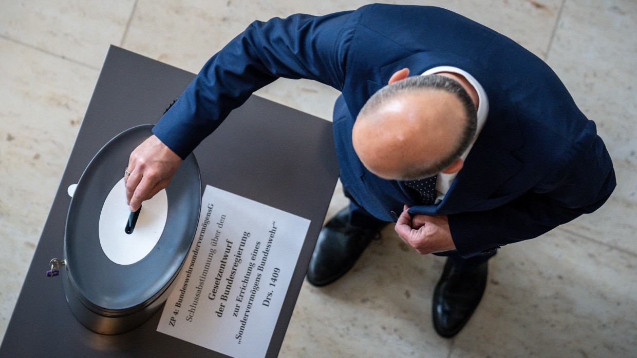 Bundeskanzler Olaf Scholz wirft am Freitag im Bundestag seine Stimmkarte zur Schlussabstimmung für die Grundgesetzänderung zum Sondervermögen der Bundeswehr ein.