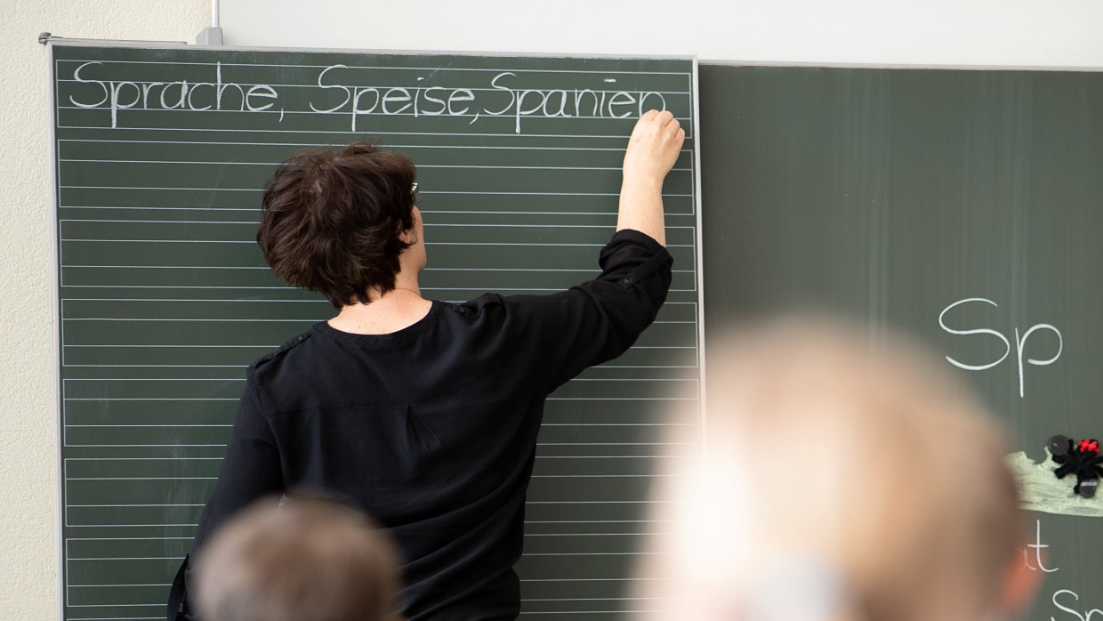 Eine Lehrerin schreibt in einer Schule Worte an eine Tafel.