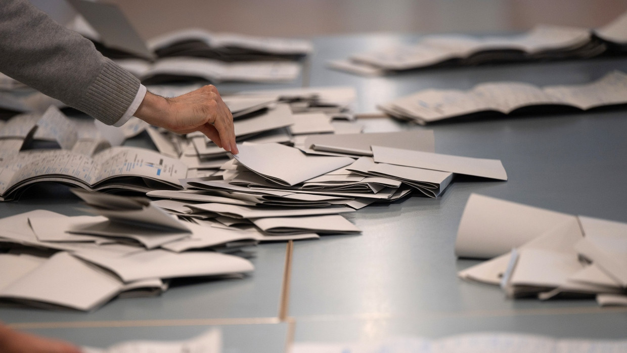 Wahlhelfer und Wahlhelferinnen zählen in einem Wahllokal Stimmzettel für die Bundestagswahl aus.