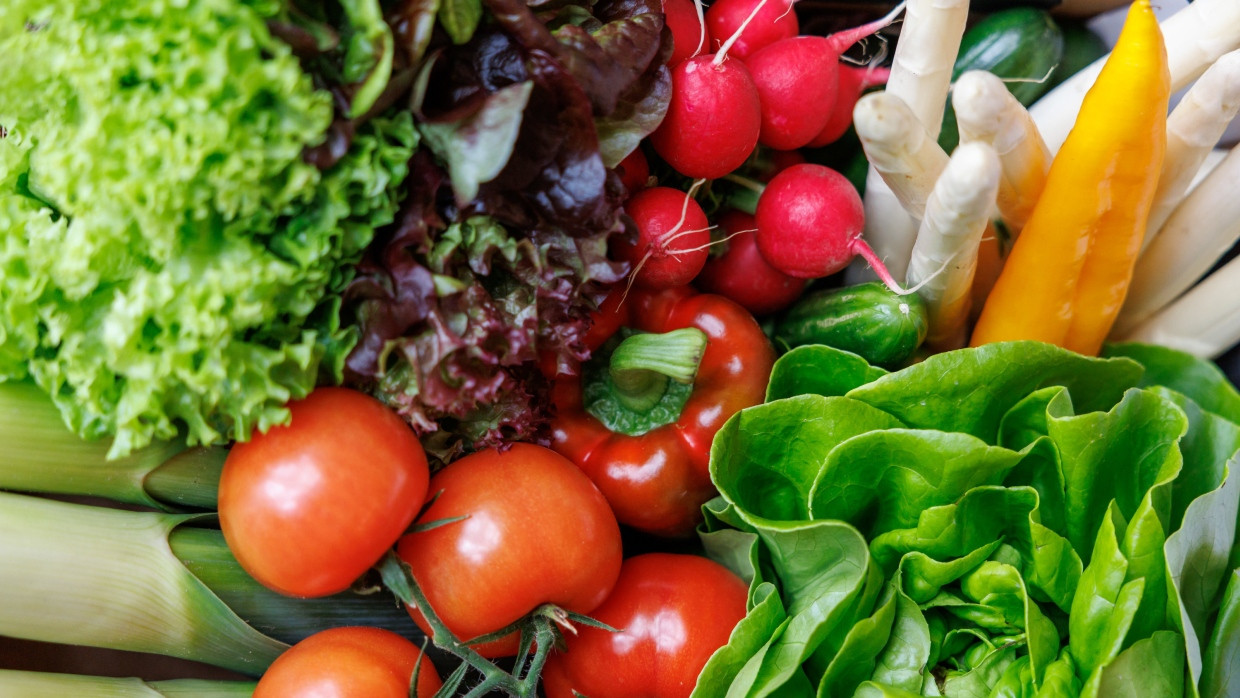 Spargel, Salate, Tomaten, Gurke, Radieschen, Spitzpaprika und Lauch liegen in einer Kiste.