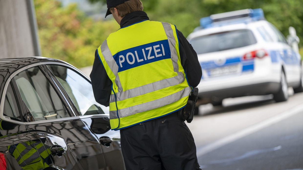 Ein Polizist kontrolliert am Grenzübergang Kiefersfelden ein aus Österreich kommendes Auto.