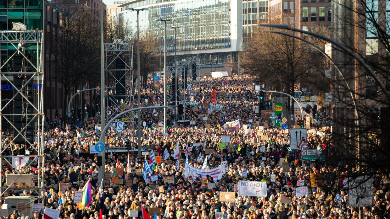 Mit Fahnen und Plakaten stehen die Demonstrierenden bei einer Demonstrationen gegen Rechtsextremismus am 28.01.2024 auf der Ludwig-Erhard-Straße in Hamburg vor der Bühne.