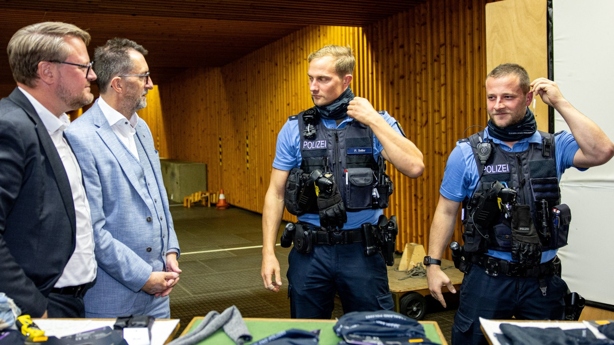 Der saarländische Innenminister Reinhold Jost (SPD, 2.v.l.) übergibt mit Staatssekretär Torsten Lang (l.) der saarländischen Polizei Schnittschutzschals und die neue Dienstwaffe SFP9 von Heckler & Koch. Zwei Polizeibeamten demonstrieren die Trageweise der Schnittschutzschals.