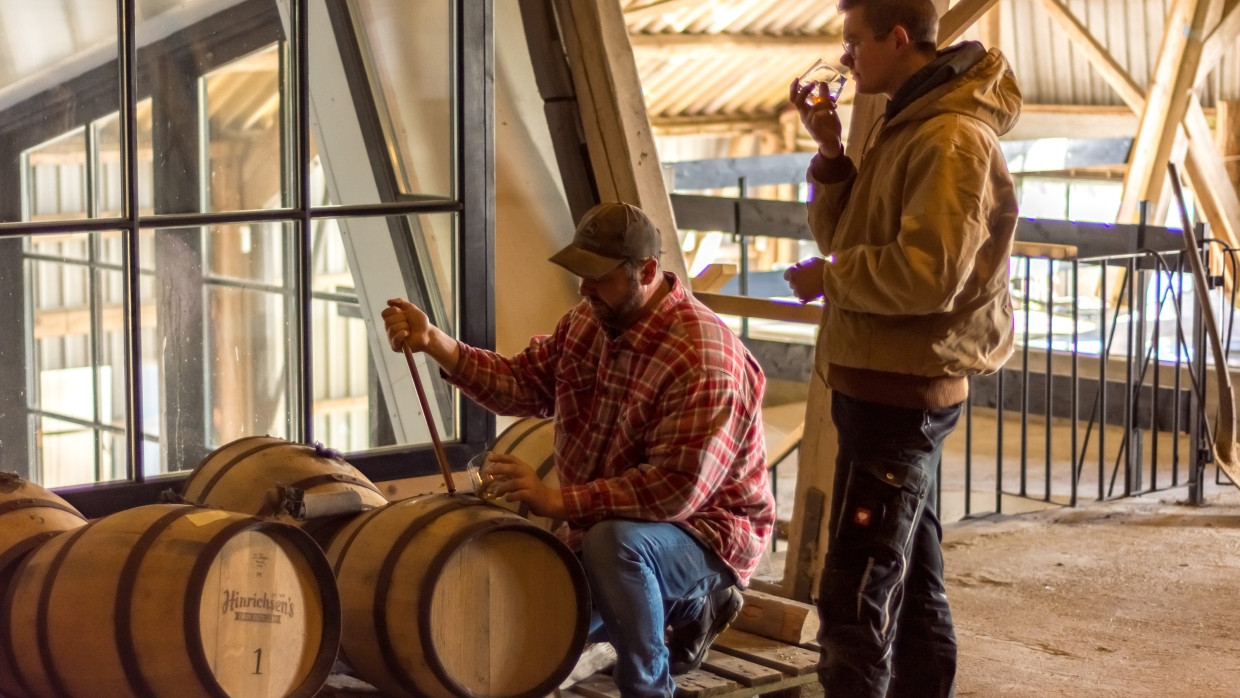 Sláinte: Jan Hinrichsen (kniend) und ein Mitarbeiter verkosten Singe Farm Whisky aus der Destillerie in Dunsum auf Föhr.