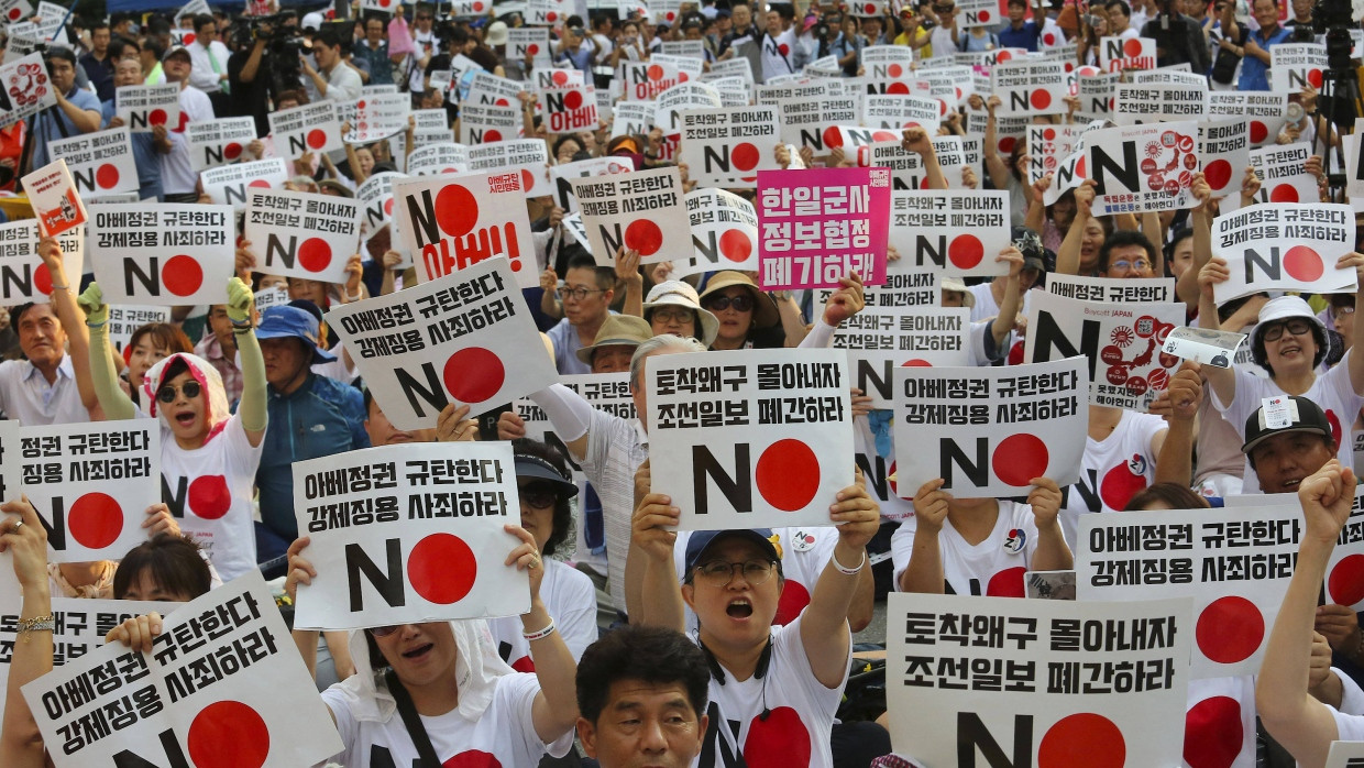 Demonstranten mit Schildern mit der Aufschrift „Wir verurteilen den japanischen Premierminister Shinzo Abe“