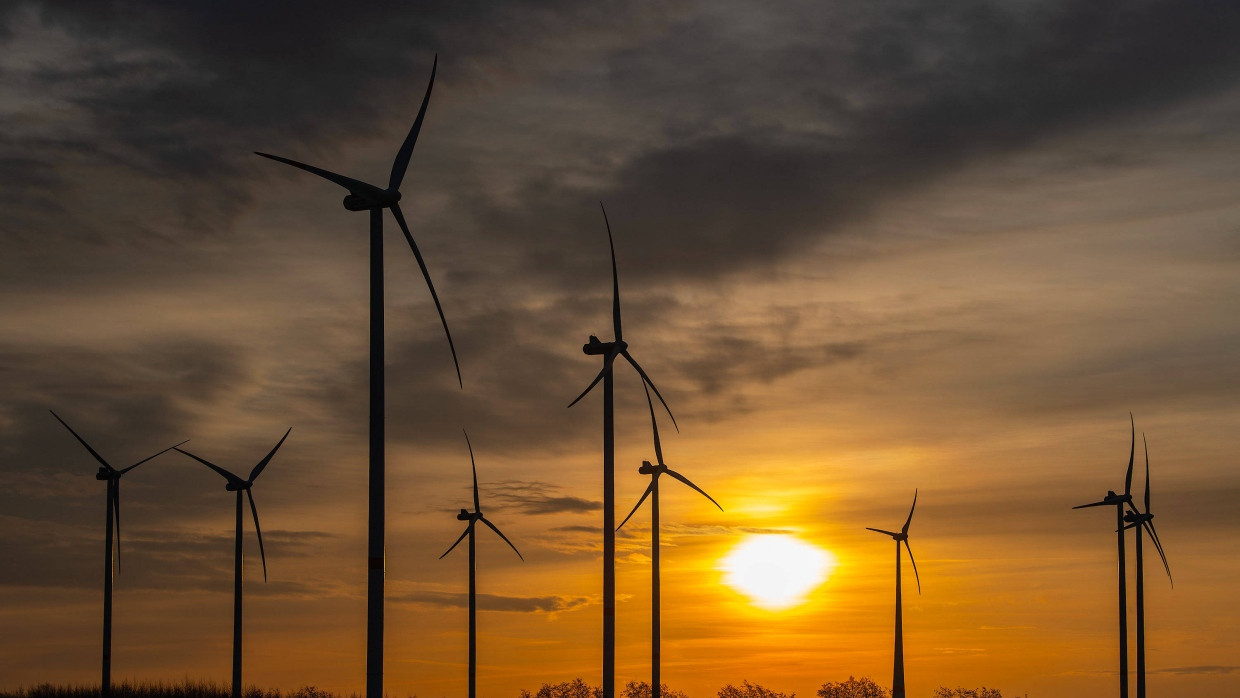 Die Sonne leuchtet beim Sonnenaufgang zwischen Wolken über dem Windpark „Odervorland“ im Landkreis Oder-Spree.