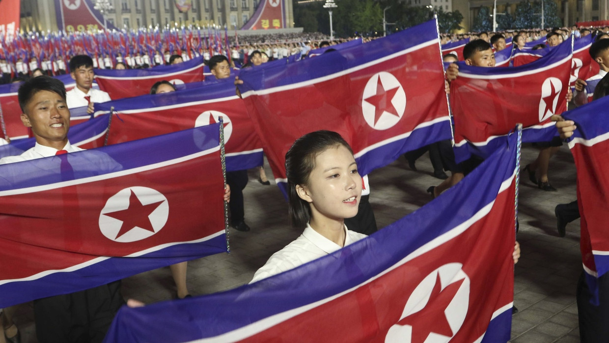 Nordkoreaner marschieren mit ihrer Nationalflagge in Pjöngjang, Nordkorea, um den 76. Jahrestag der Gründung des Landes zu feiern.