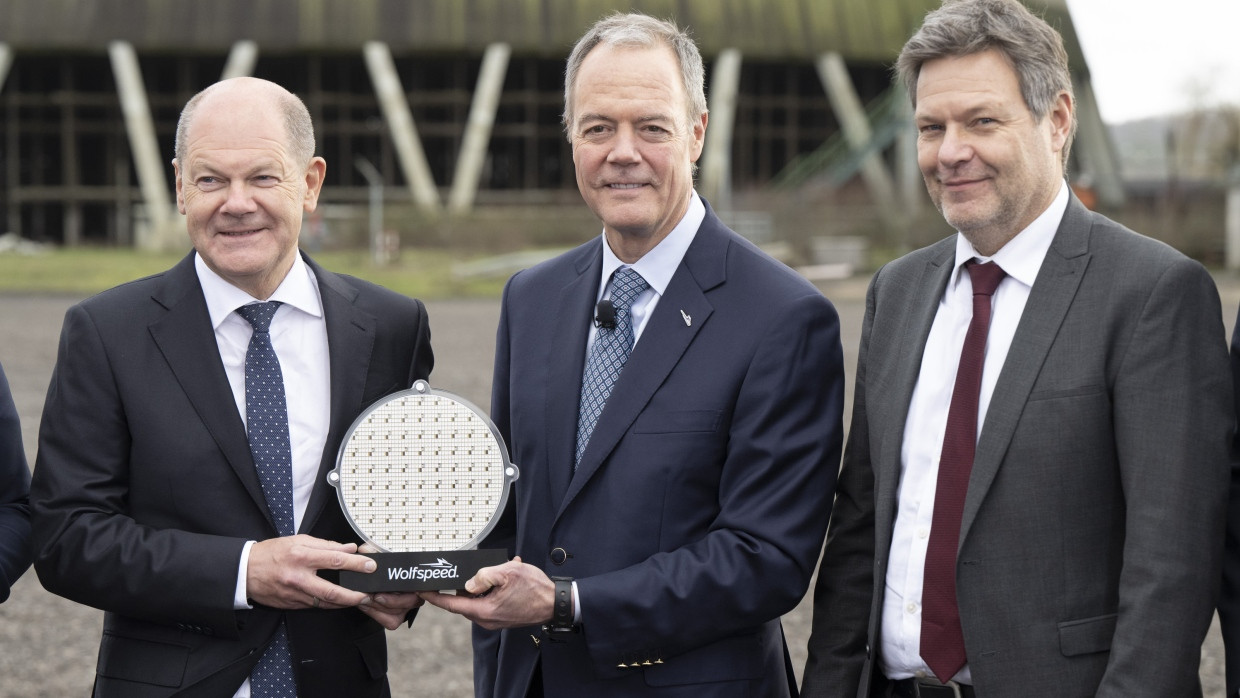 Bundeskanzler Olaf Scholz (l-r, SPD), Gregg Lowe, CEO von Wolfspeed und Robert Habeck (Bündnis 90/Die Grünen), Bundesminister für Wirtschaft und Klimaschutz, halten auf einer Veranstaltung am geplanten Standort der Wolfspeed-Chipfabrik in Ensdorf im Saarland einen Waver.