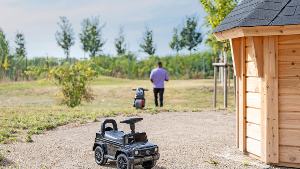 Auch ein Ort zum Spielen: Im Lebensgarten der Hochtaunus-Kliniken stehen zwei Spielzeugfahrzeuge neben der Holzhütte.