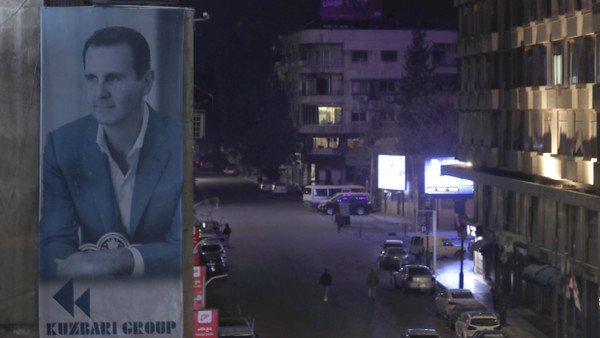 Großes Plakat des Gewaltherrschers Assad über den leeren Straßen von Damaskus am Samstagabend