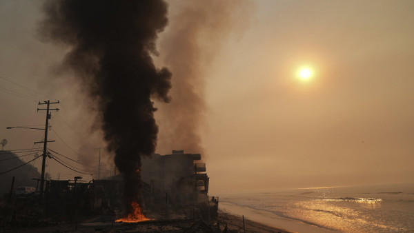 Malibu im Januar 2025: Rauch steigt von einem brennenden Grundstück am Strand auf.