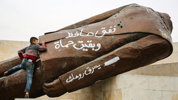 Ein Kind erklimmt am 7. Dezember in Hama die abgerissene und enthauptete Statue des ehemaligen syrischen Präsidenten Hafis al-Assad.