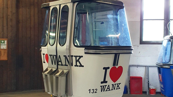 Dieses von der Bayerischen Zugspitzbahn zur Verfügung gestellte Foto zeigt eine Gondel der Wankbahn mit dem Logo „I love Wank“ in einer Seilbahnstation.