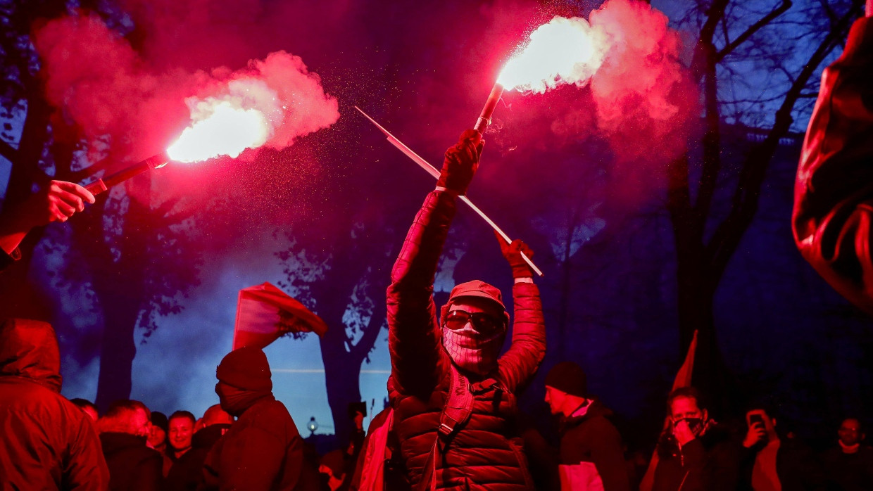 Eine Person verbrennt Bengalos während einer Demonstration gegen die neuen Beschränkungen in Österreich.