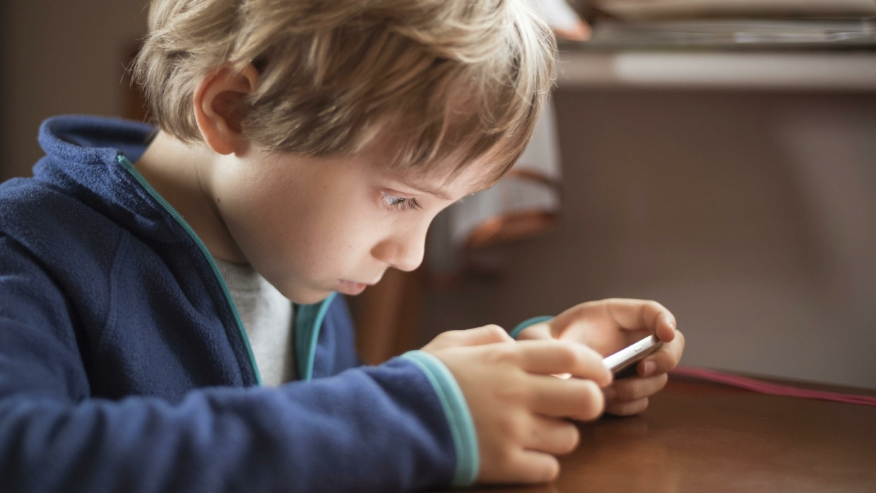 Ein Junge schaut auf ein Smartphone. (Symbolbild)