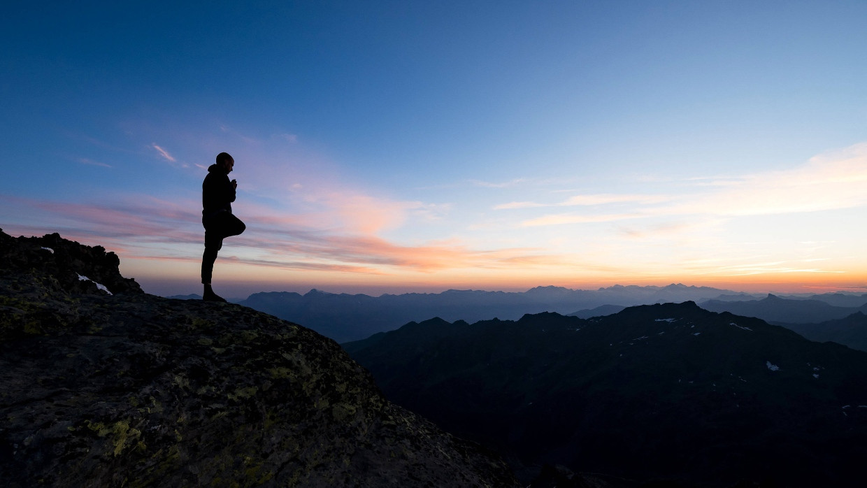 Schweiz: Emilien Badoux, Schweizer Ski- und Yogalehrer, praktiziert Yoga bei Sonnenaufgang auf dem Gipfel des Mont Fort.