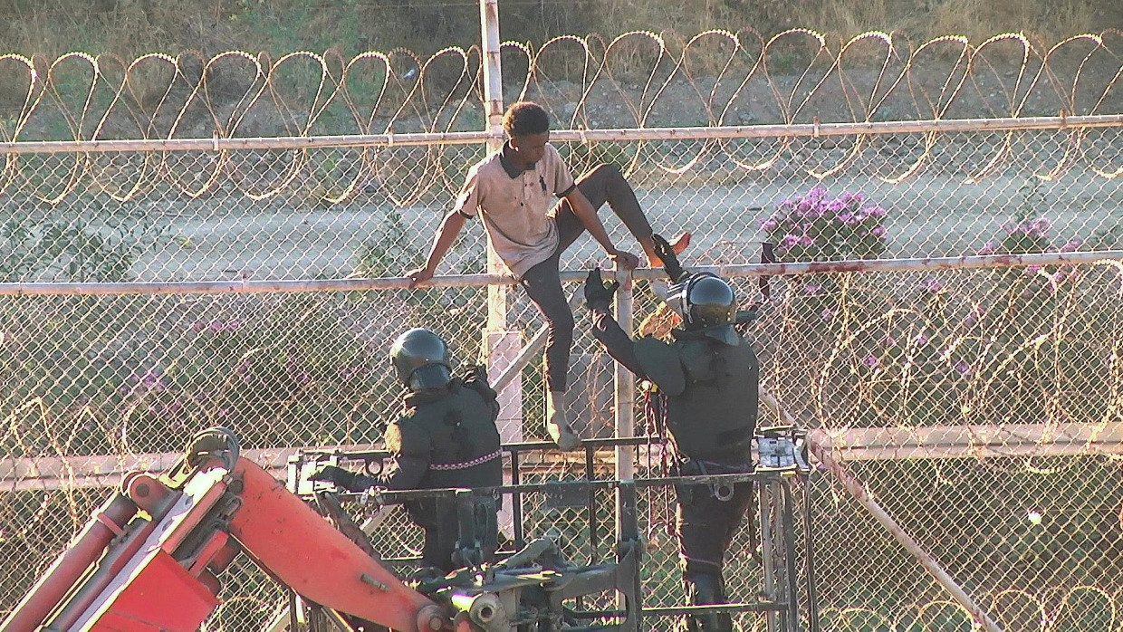 Ein afrikanischer Migrant klettert über den Grenzzaun an der spanischen Enklave Ceuta, die an Marokko grenzt.