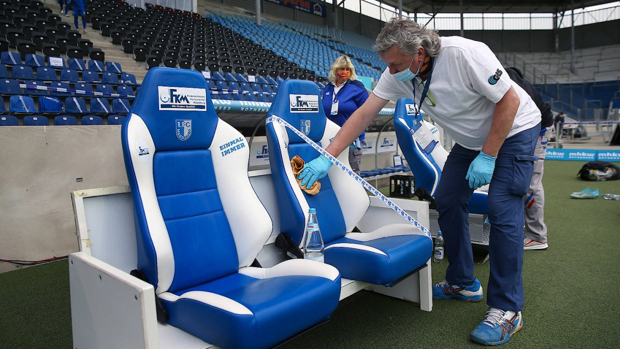 Ein Mitarbeiter des 1. FC Magdeburg desinfiziert die Trainerbänke im eigenen Stadion.