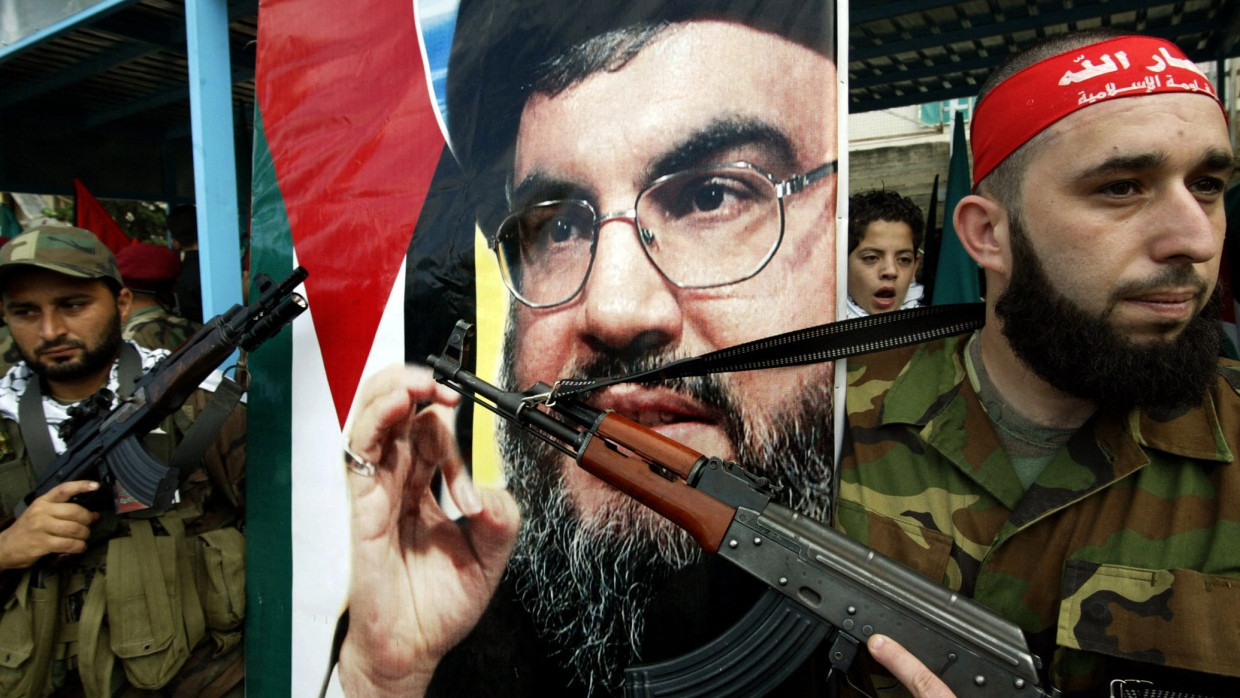 Bewaffnete Palästinenser demonstrieren neben einem Poster des getöteten Hizbullah-Führers Hassan Nasrallah.