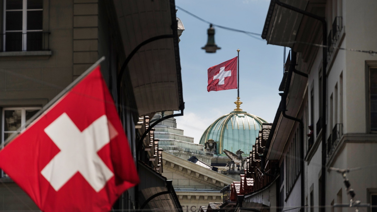 Die Schweizer Nationalfahne weht auf den kleinen Kuppeln auf dem Bundeshaus in Bern.