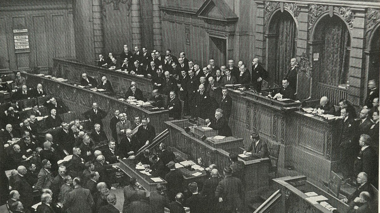 Der Oppositionsführer am Rednerpult: Alfred Hugenberg spricht im Reichstag, Reichskanzler Hermann Müller und seine Minister Julius Curtius, Joseph Wirth und Adam Stegerwald (von rechts) hören zu. Erst unter dem Reichskanzler Adolf Hitler gelangte Hugenberg an die Regierungsmacht.