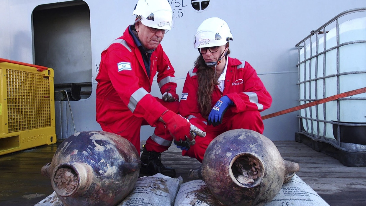 Dieses von der israelischen Antikenbehörde (IAA) veröffentlichte Foto zeigt Jacob Sharvit (l) und Dr. Karnit Bahartan mit den antiken Gefäßen, die auf dem ältesten bekannten Tiefseeschiff der Welt transportiert wurden.